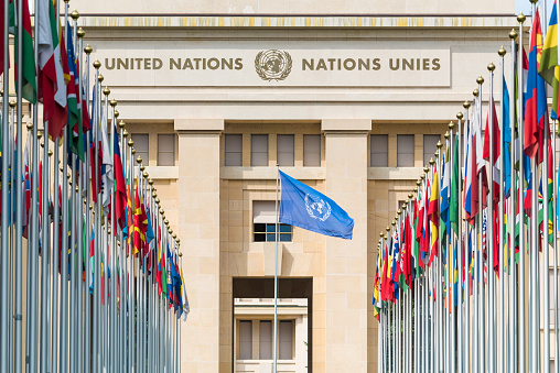 Flags of the 193 member countries of the United Nations flying from a row of flag poles at the United Nations headquarters in Geneva, Switzerland