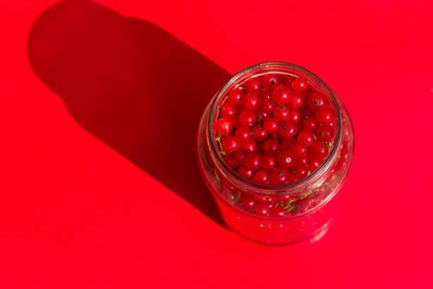 top view jar full of red currant berries on a red background