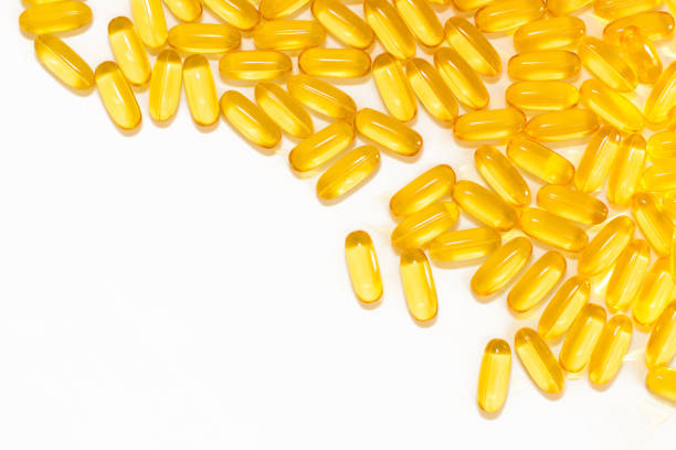 Fish oil isolated on white background. Yellow transparent medical capsules with fish oil for health and good. Vitamin D and A. Very useful for women. Medical background with pills. Place for text.