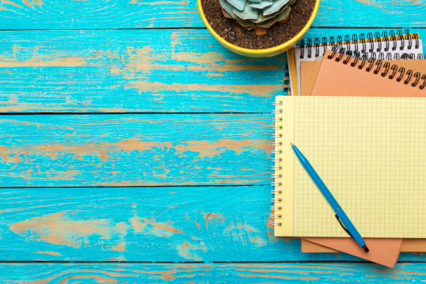 istock Top view workspace with blank notebook and pen on wooden table background 1023304118