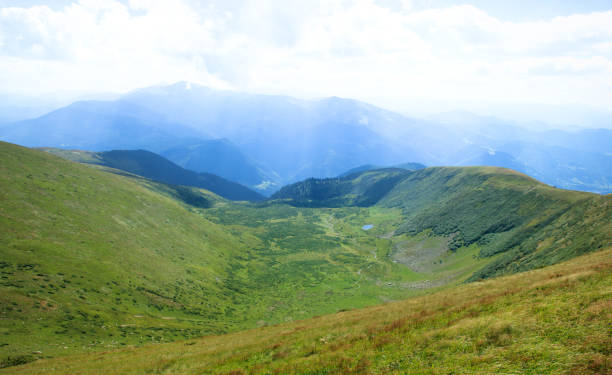 istock green valley in the mountains, blue clouds on the background 1023322500