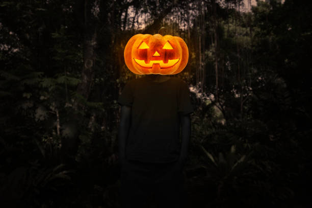 Pumpkin monster head on man body standing over dark forest and tree, Halloween concept