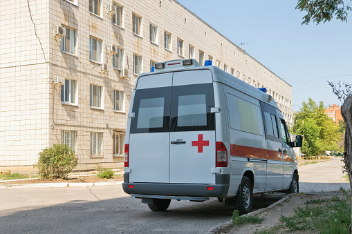 A new white ambulance van is parked next to the hospital complex