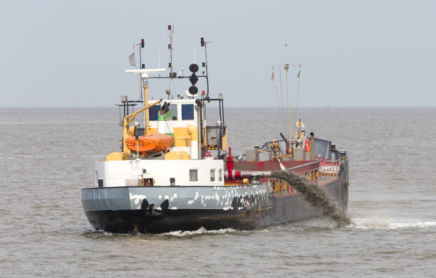 istock Sand dredging boat drawing away from coast shoreline 1023338974