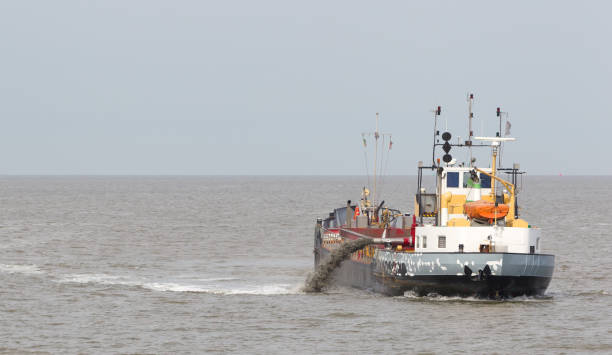 istock Sand dredging boat drawing away from coast shoreline 1023339012