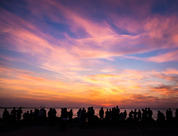 istock Crowd of silhouetted people watching sunrise or sunset 1023356168