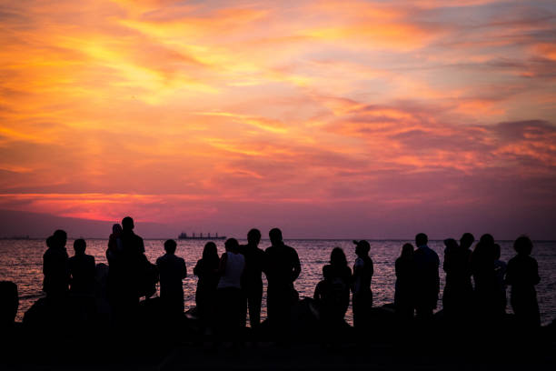 istock Crowd of silhouetted people watching sunrise or sunset 1023356186