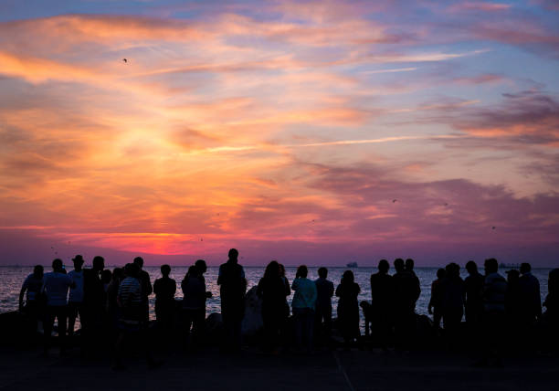 crowd of silhouetted people watching sunrise or sunset - sea zen like landscape water imagens e fotografias de stock