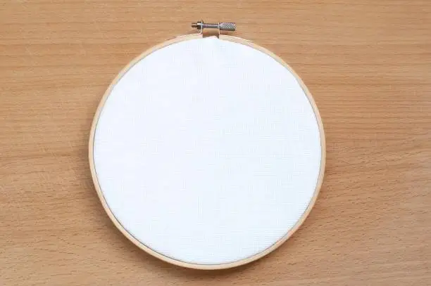 Round wooden hoop with a white cloth on a wooden background.