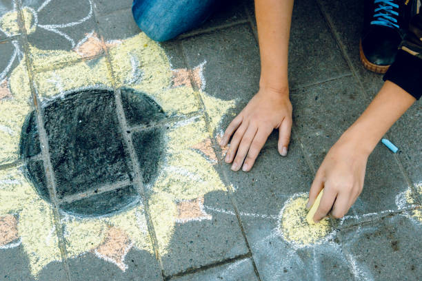 istock Child's hand draws a chalk flower and asphalt. 1023364780