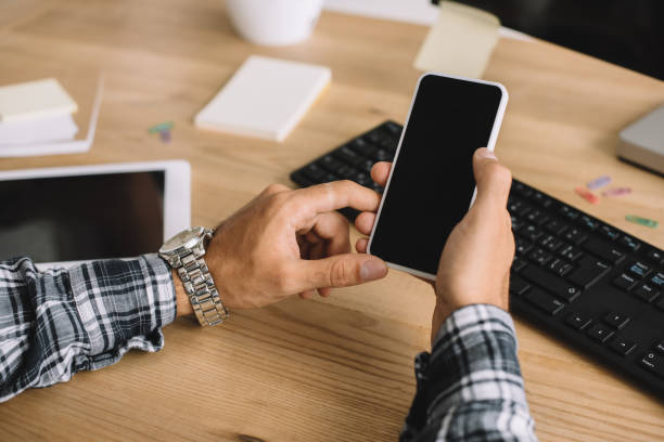 istock cropped shot of man using smartphone with blank screen at workplace 1023378732