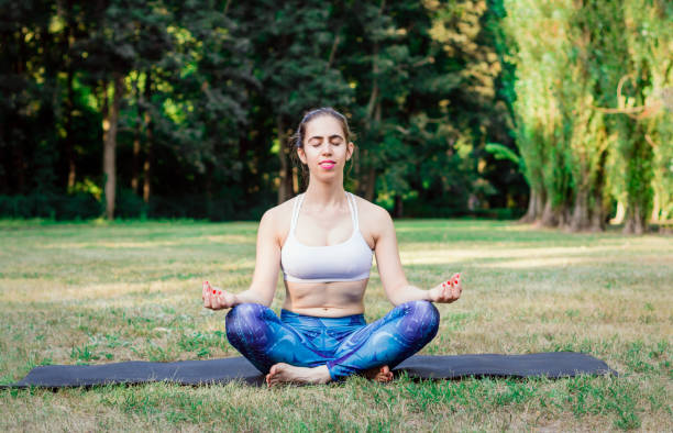 istock Young woman practicing yoga in nature. Sitting on green grass. 1023383764