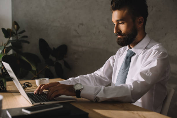istock handsome bearded businessman using laptop in office 1023388058
