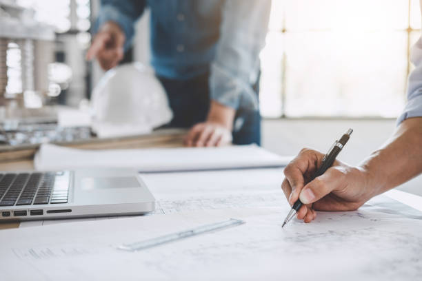 istock Hands of architect or engineer working on blueprint meeting for project working with partner on model building and engineering tools in working site, Construction concept 1023391330