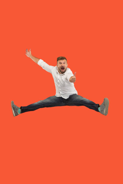 istock Freedom in moving. handsome young man jumping against orange background 1023393822