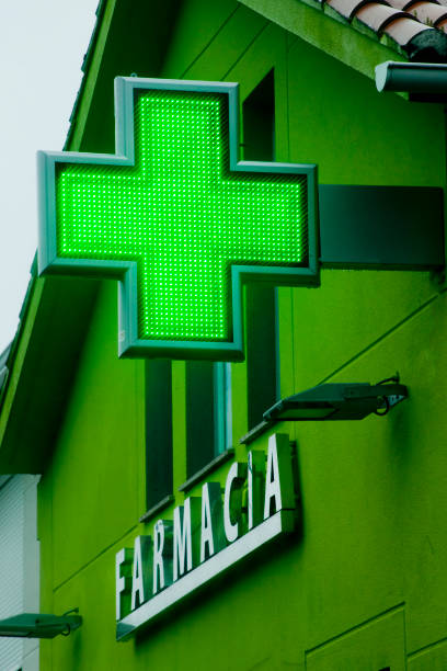 simbolo della farmacia in strada, croce verde e dettaglio della facciata della casa verde.. - green cross foto e immagini stock