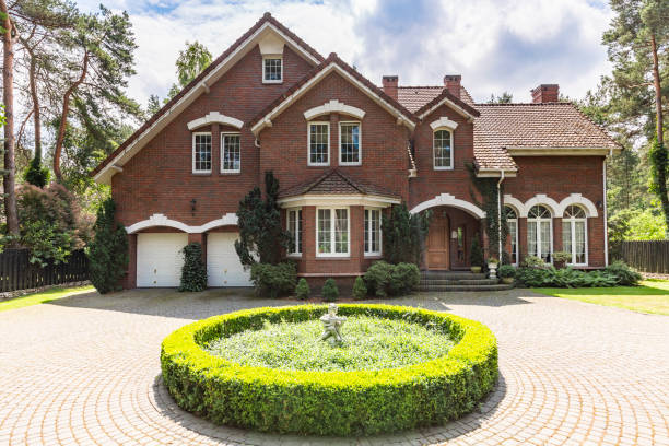 vista frontal de uma casa clássica estilo inglês de tijolo vermelho com um telhado íngreme, janelas grandes e uma entrada circular com uma decoração de canteiro de flores na frente. - brick wall paving stone brick wall - fotografias e filmes do acervo