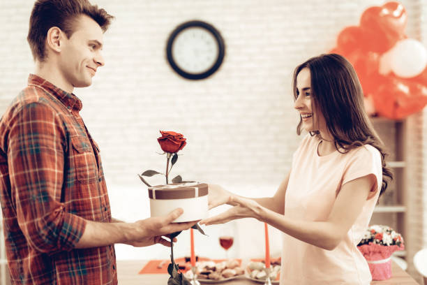 guy makes a gift to girlfriend on valentine's day. - rose rosé women valentines day imagens e fotografias de stock