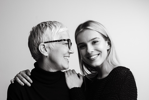 Studio shot of mother and daughter. Both of them wearing black. Black and white image.