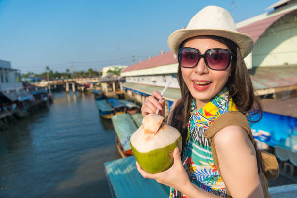 istock woman holding a coconut and sip with a straw 1023457282