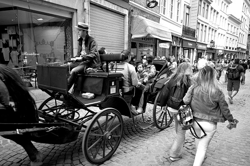 Horse and carriage in Bruges. It is walking on the cobbles near the Grand Place with tourists on board.