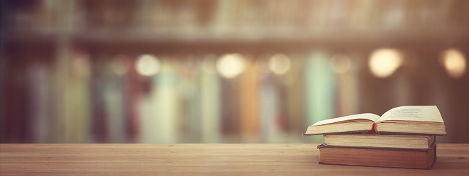 back to school concept. stack of books over wooden desk in front of library