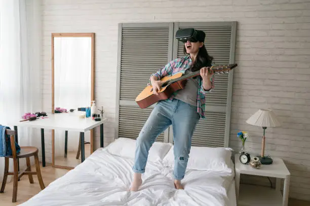 Female modern Asian woman leaning her body back and holding her wooden guitar and shouted and yelled as her room is a personal concert.