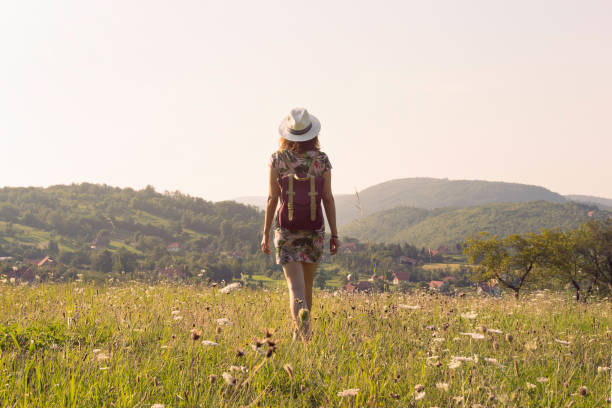 Traveler girl walking through fields.