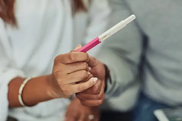 Closeup shot of an unrecognizable couple holding a pregnancy test at home