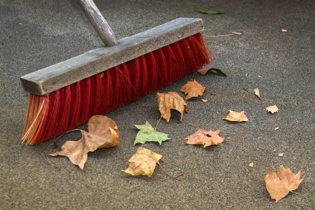 A Wooden Broom sweeping together some Colorful Leaves