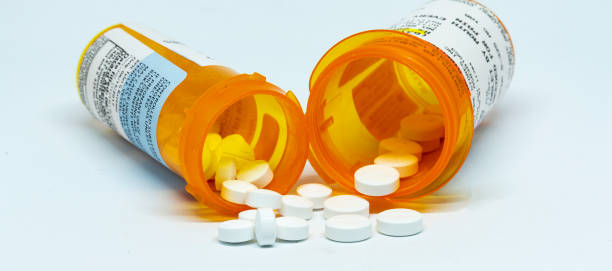 Two prescription pill bottles with pills spilling out Two perscription bottles with pain pills spilling out of them with a white background. Opioid Treatment stock pictures, royalty-free photos & images