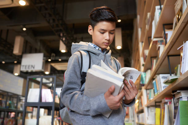 istock School boy standing in library holding books 1023486502