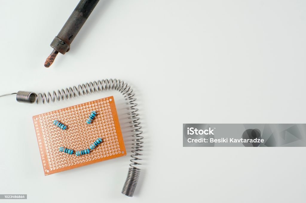 Emoji face on a blank circuit board Emoji face on a blank circuit board with soldering iron Accuracy Stock Photo