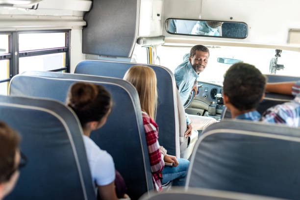 groupe d’érudits teen riding school bus et en discutant avec l’heureux conducteur mature - métier du transport photos et images de collection