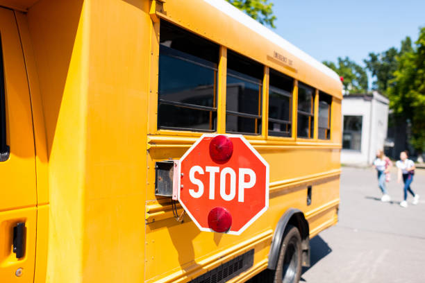 istock partial view of school bus with stop sign standing on parking with blurred students running on background 1023496324