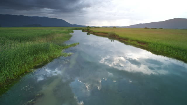 AERIAL Marsh river reflecting grey stormy clouds on its peaceful surface