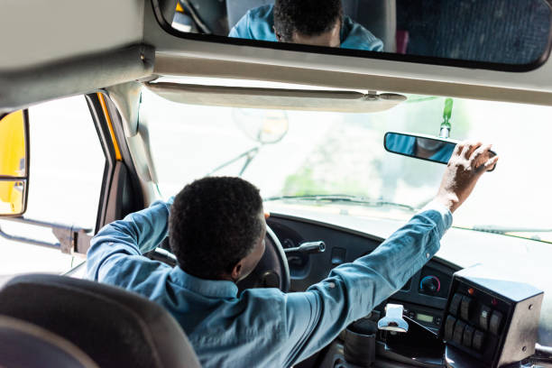 mature african american driver adjusting back view mirror at bus
