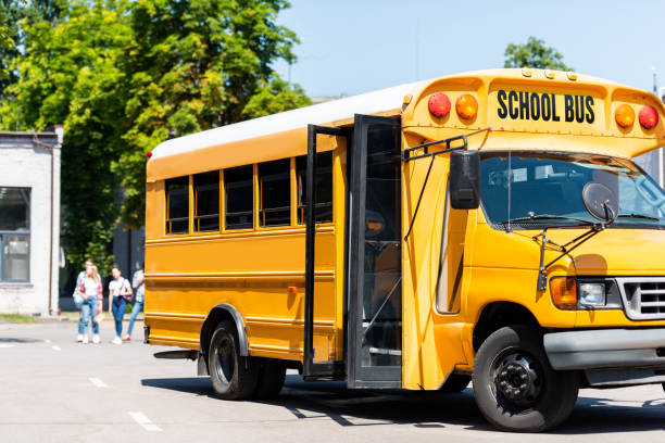 istock school bus standing on parking with blurred students walking on background 1023496354
