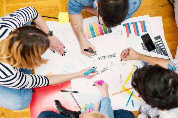 istock Group of young modern designers sitting on a floor and making new plans. 1023505598