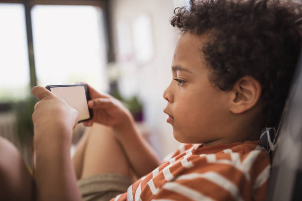 istock Cute mixed - race boy playing games on mobile phone 1023508348