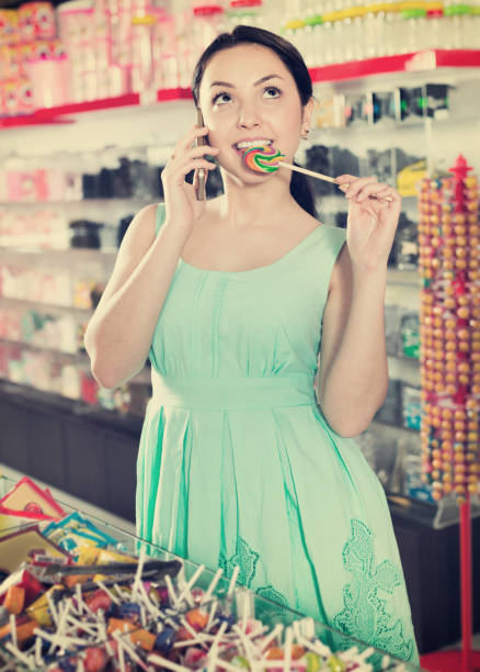 istock Young woman speaking by mobile   and picking different candies 1023508822