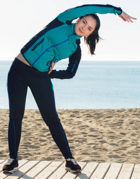 istock Woman doing exercises on beach by ocean at daytime 1023508882