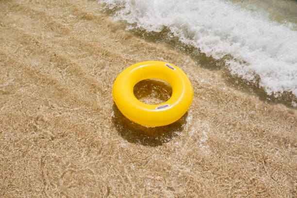 istock Yellow Rubber Ring at the Shoreline with incoming wave. 1023510022