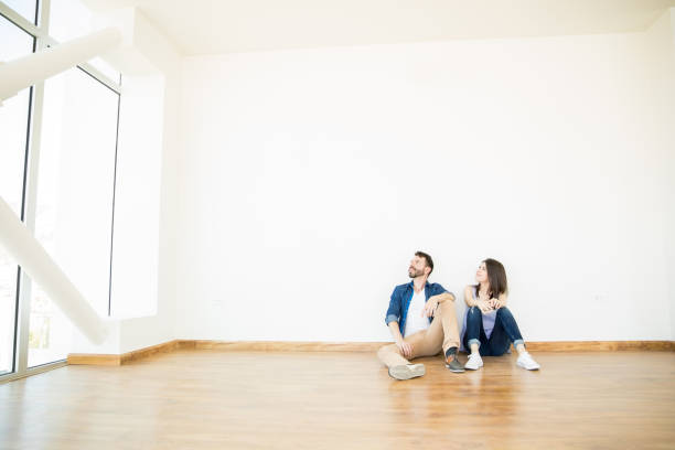 istock Couple Looking Away While Sitting Against Wall In New Apartment 1023517578
