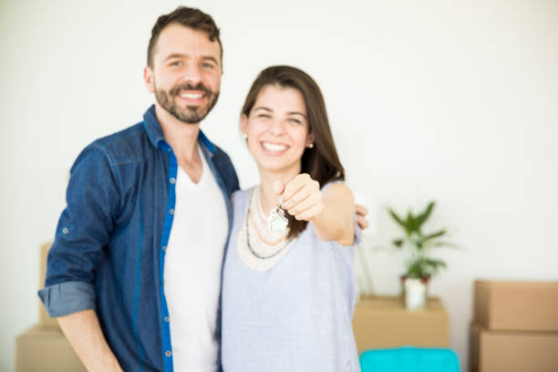 istock Couple Showing New House Keys While Standing At Home 1023517722