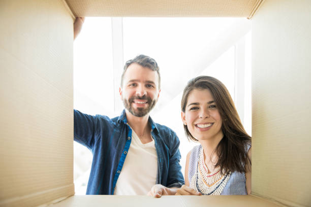 istock Couple Smiling While Looking Into Cardboard Box In New Home 1023517820