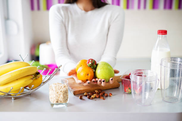 istock Fresh and diverse fruit is being held by a young woman near a kitchen counter that has all the ingredients one smoothie should. 1023525068