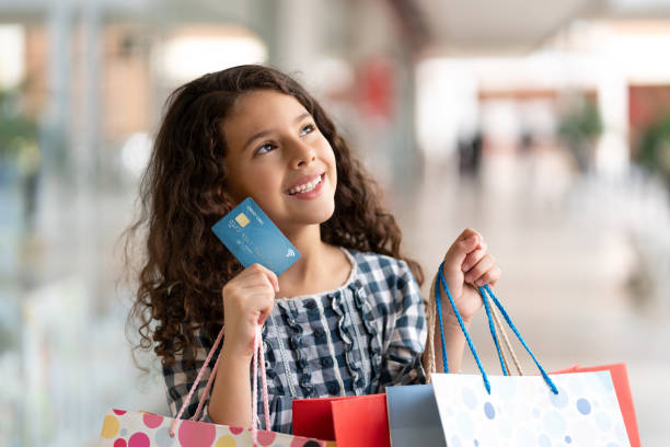 クレジット カードやショッピング バッグを押しながら離れて見ている空想美しい少女 - paying children only retail childhood ストックフォトと画像