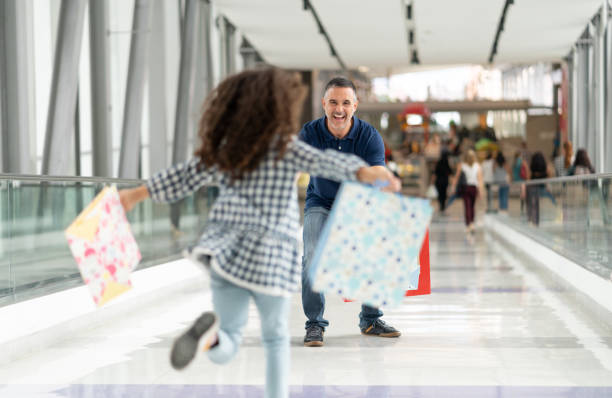 Loving father greeting his little daughter at the airport while she runs towards him Loving father greeting his little daughter at the airport while she runs towards him holding gifts airport hug stock pictures, royalty-free photos & images