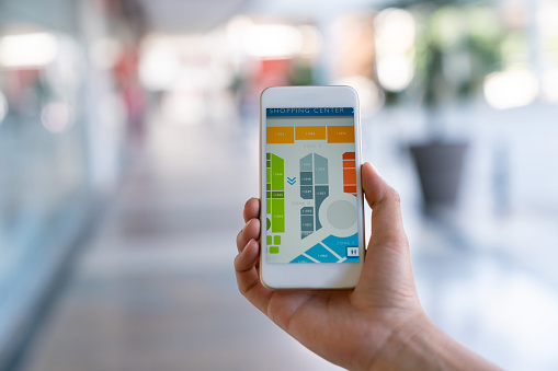 Close up of unrecognizable person holding a mobile phone with a shopping center map on screen